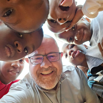 Br. Adam Neri smiling with children in Tanzania.